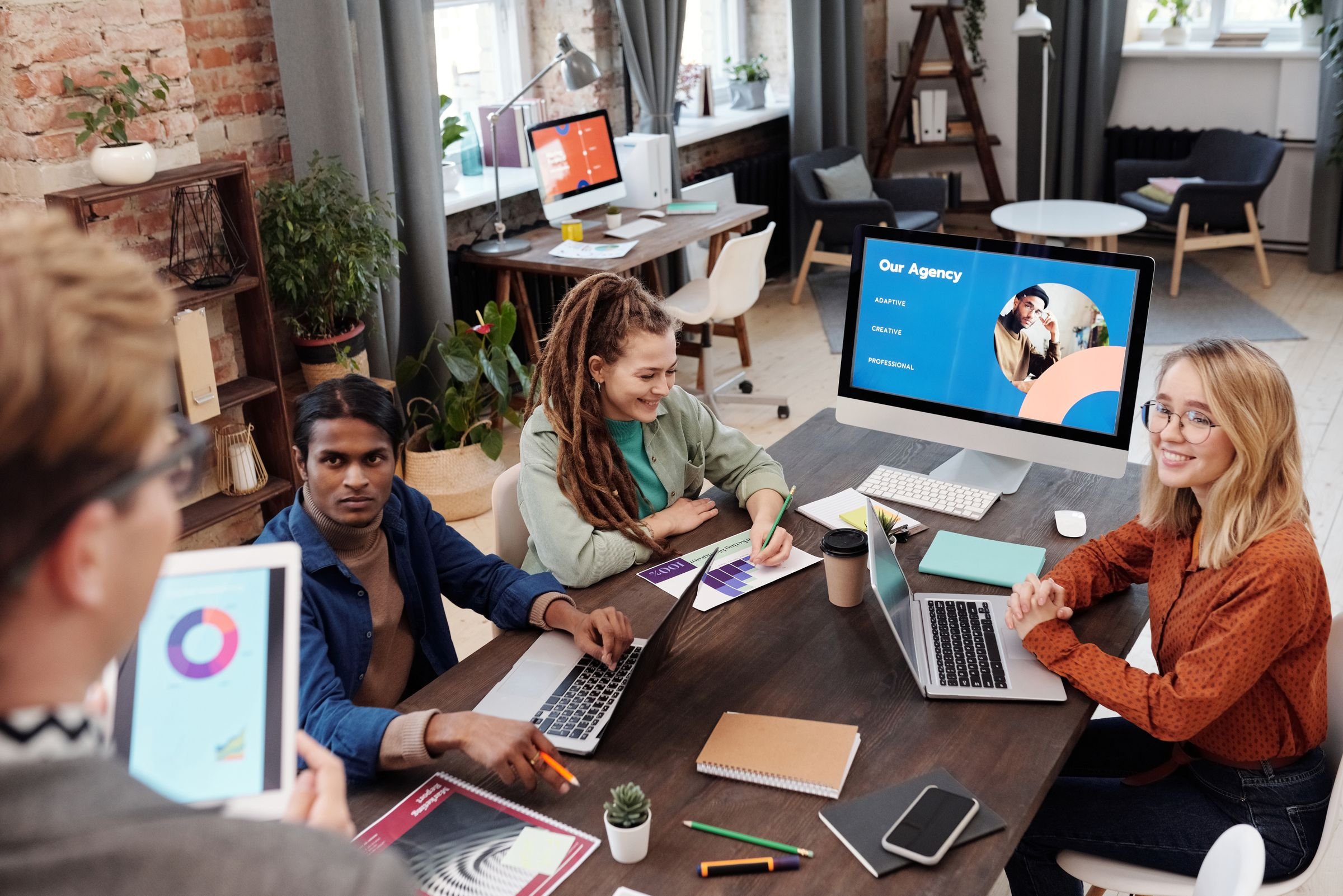 A marketing agency team working together around a table with laptops