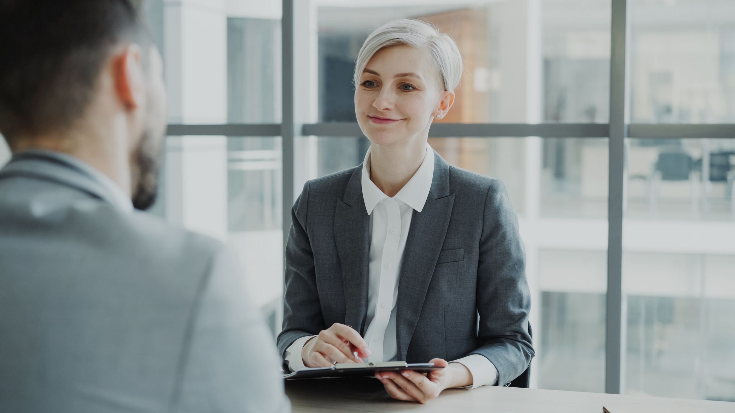 An interviewer talking with a candidate across a table in an office
