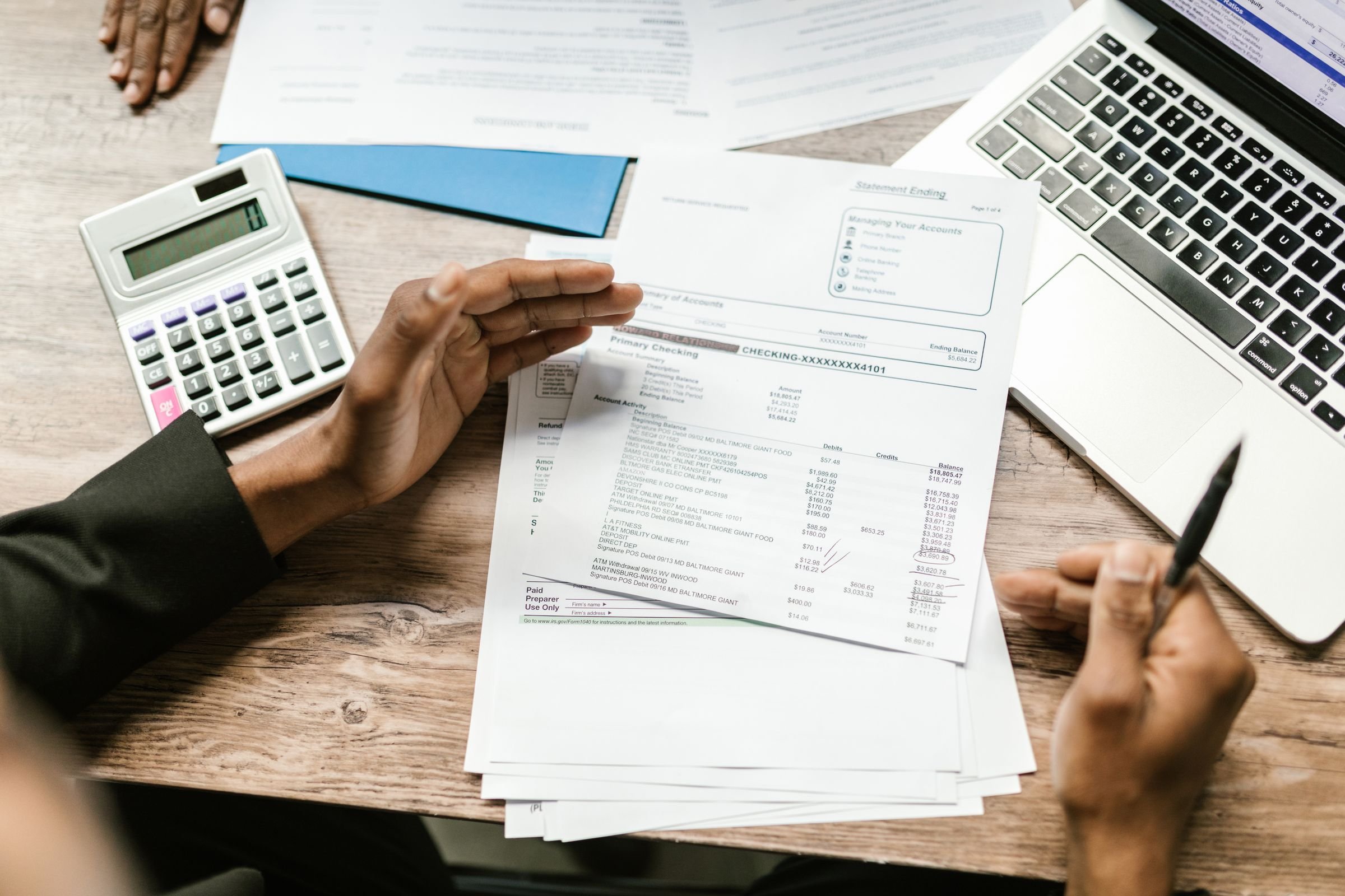 Invoices, a calculator and a laptop on a desk while someone checks the figures