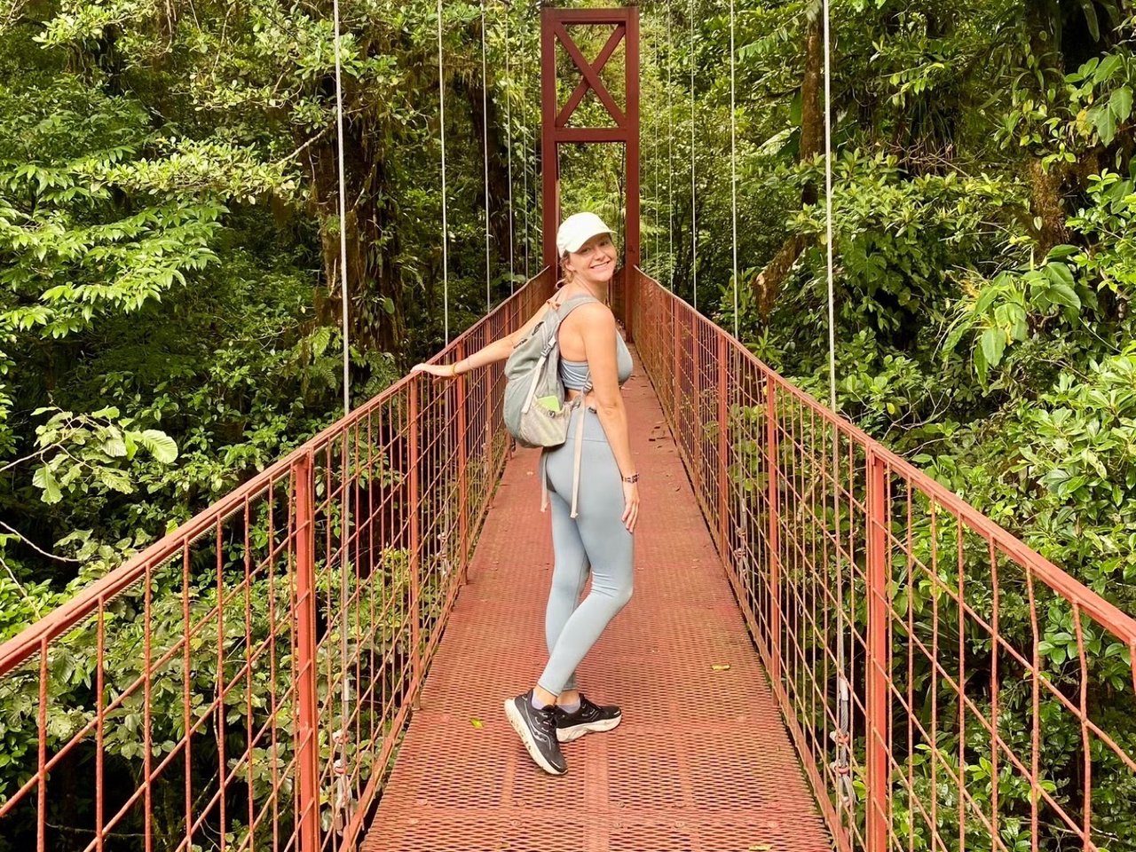 Kelly Brown smiling on a red suspension bridge in the Costa Rican cloud forest.