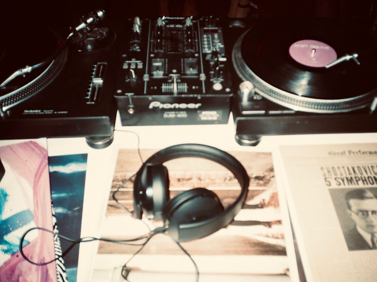 Turntables, vinyl records and headphones on a DJ setup.