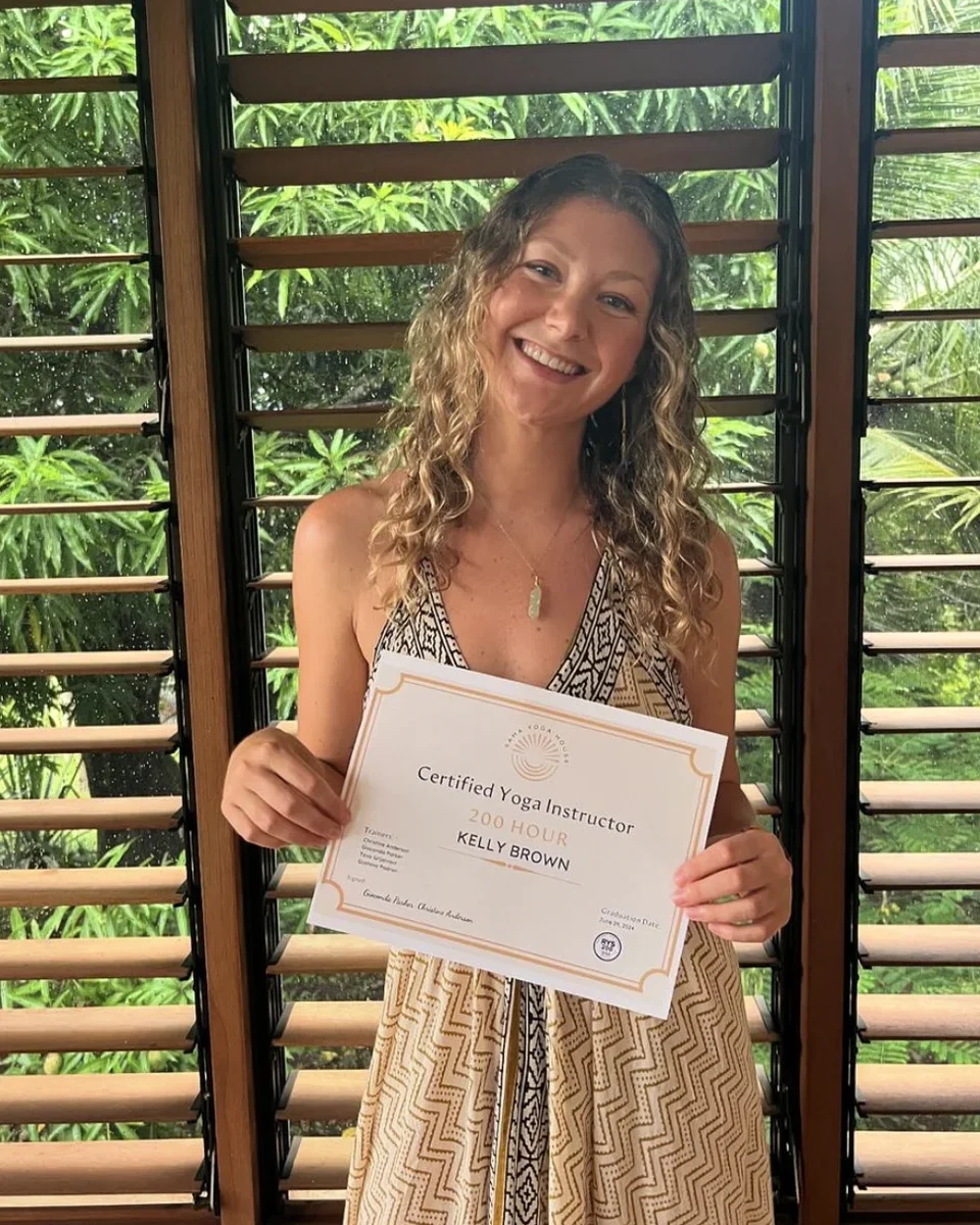 Kelly Brown holding her 200-hour yoga instructor certificate.